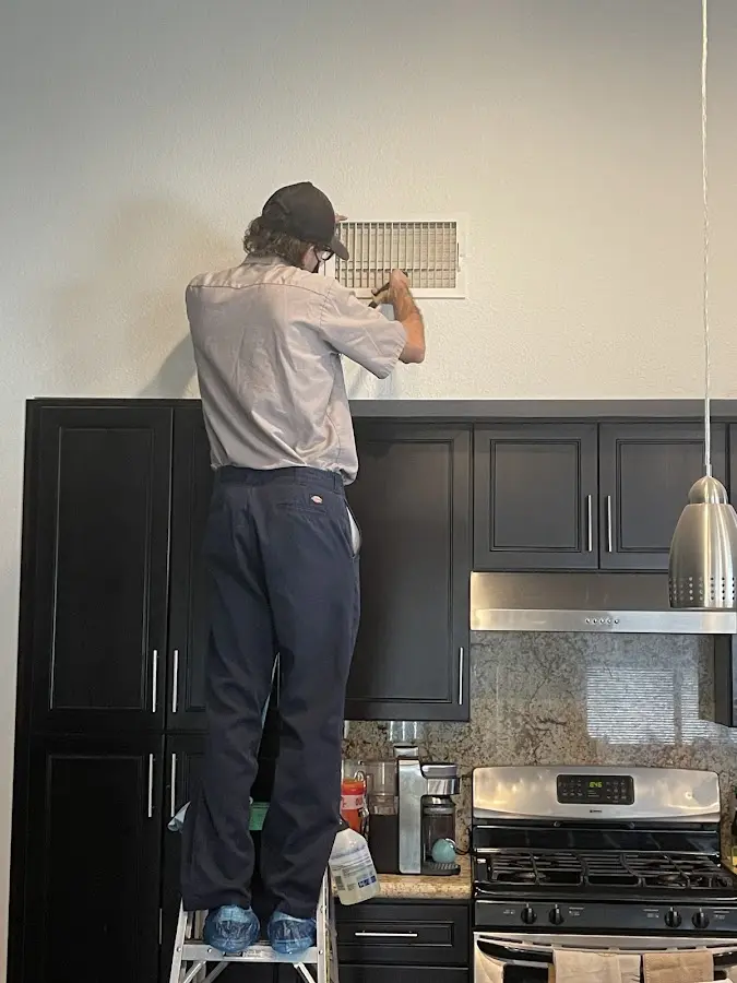 Technician inspecting an air vent during HVAC service in Mount Lebanon
